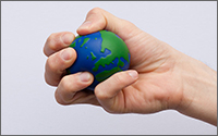 A hand squeezing a stress ball that looks like Earth.