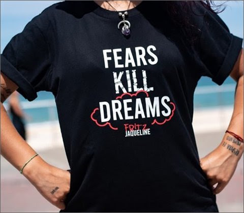 A woman wearing a black shirt with white text that states, 'Fears Kill Dreams.'