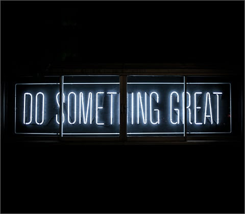 A blue neon sign that says, 'Do Something Great' in front of a black background.