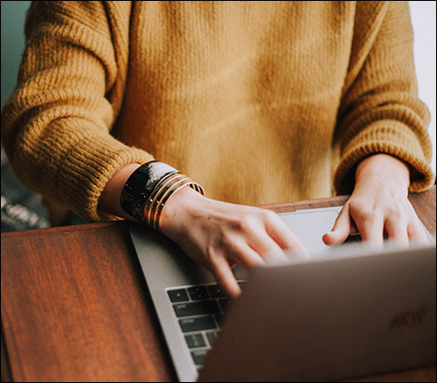 A person sitting at a table working on their laptop.